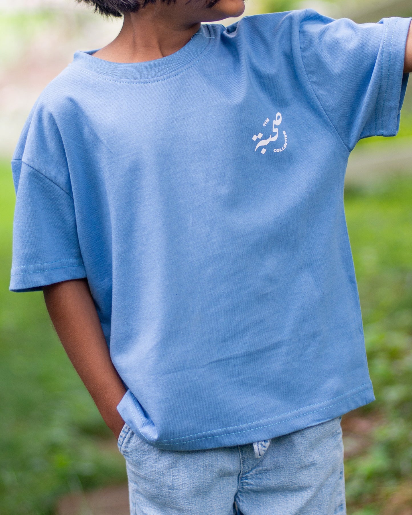 Child wearing a blue t-shirt with a logo outdoors